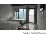 The image shows a bedroom with two single beds in it. The beds are covered with white linens and have white pillows on top. T...