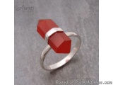 The image is of a silver ring with a large red gemstone in the center. The gemstone appears to be faceted and has a smooth, p...