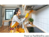 In this image, we can see a young woman wearing a yellow apron and yellow gloves, working in a kitchen. She is holding a tool...