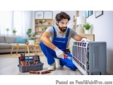 In this image, we can see a man wearing blue overalls and safety goggles, kneeling on the floor in front of an air conditioni...