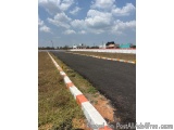 The image shows a long, straight road with a white and orange striped barrier on one side. The road appears to be empty, with...