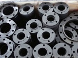 The image shows a pile of black metal flanges or flanges stacked on top of each other. The flanges are circular in shape and...
