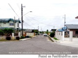 The image shows a street view of a residential area. The street is empty and there are no cars or people visible. On the left...