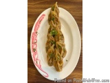 The image shows a plate of dumplings on a wooden table. The plate is white with a pink floral design around the edge. On the...