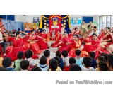 The image shows a group of children performing a dance in a classroom. The children are dressed in traditional Indian attire,...