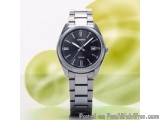 The image is a photograph of a wristwatch with a black dial and a silver bracelet. The watch has a round face with a silver b...