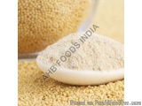 The image shows a pile of yellow-colored granules, which appear to be sesame seeds, on a white plate. The granules are arrang...
