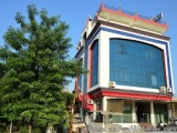 The image shows a modern building with a blue and white facade. The building has a red roof and a large window on the second...