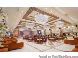 The image shows the interior of a luxurious hotel lobby. The lobby has a high ceiling with a unique design that is decorated...