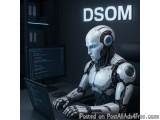 The image shows a robot sitting at a desk in front of a computer monitor. The robot is white with blue eyes and has a futuris...
