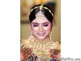 The image is a close-up portrait of a beautiful Indian bride. She is wearing a traditional Indian bridal outfit with a gold n...