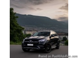 The image shows a black Mercedes-Benz SUV parked on the side of a road. The car is facing towards the left side of the image...