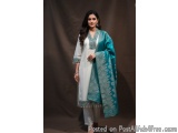 The image shows a young woman wearing a traditional Indian outfit. She is wearing a white kurta with a blue dupatta draped ov...