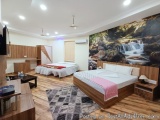 The image shows a modern and spacious bedroom with a large mural on the wall. The mural depicts a waterfall cascading down a...
