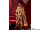 The image shows a woman standing in a luxurious room with red curtains and a chandelier hanging from the ceiling. She is wear...