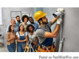 The image shows a group of people gathered around a man wearing a yellow hard hat and overalls, who is holding a security cam...