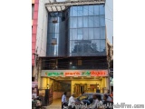 The image shows a modern building with a glass facade. The building is located on a busy street with other buildings and cars...