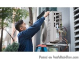 In this image, we can see a man wearing a blue uniform and a face mask, working on an outdoor air conditioning unit. He is st...