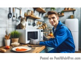 The image shows a young man in a blue uniform sitting at a kitchen counter with a white microwave oven in front of him. He is...
