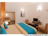 The image shows a modern and spacious bedroom with a large bed in the center. The bed has a beige headboard and a blue blanke...