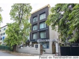 The image shows a modern building with a black and white facade. The building is located on a street corner with a tree on th...
