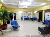 The image shows the interior of a modern office space with a high ceiling and a chandelier hanging from it. The floor is made...