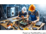 The image shows two men wearing hard hats and overalls working on a computer monitor in an office setting. They are both wear...