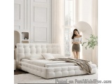 The image shows a modern and luxurious bedroom with a large white bed in the center. The bed has a tufted headboard and is co...