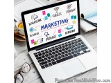 The image shows a laptop with the word "Marketing" written on the screen in different colors and fonts. The laptop is placed...