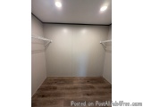 The image shows an empty room with a wooden floor and white walls. The walls are painted in a light grey color and there are...
