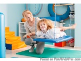 The image shows a mother and daughter playing in a playroom. The mother is kneeling on the floor and the daughter is sitting...