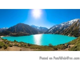 The image is a beautiful landscape of a mountain range with a large lake in the center. The lake is a deep turquoise color an...