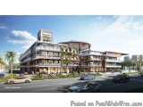 The image is a digital rendering of a modern shopping center. The building is a two-story structure with a curved roof and mu...