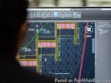 The image shows a computer screen with a 3D model of a building on it. The model appears to be a floor plan or a layout of a...