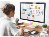 The image shows a woman sitting at a desk in front of a computer monitor. She is wearing a white shirt and has her hair tied...