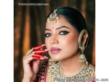 The image is a close-up portrait of a beautiful Indian woman wearing traditional Indian jewelry. She is wearing a red and gol...