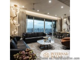 The image shows a modern living room with a large window that offers a beautiful view of the ocean. The room is furnished wit...