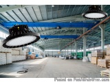 The image shows a large warehouse with high ceilings and large windows. The warehouse is filled with stacks of cardboard boxe...