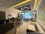 The image shows a modern office space with a large window on the right side. The window has a view of a city skyline. On the...