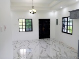 The image shows an empty room with white walls and a black door. The floor is made of marble tiles with a unique pattern. The...