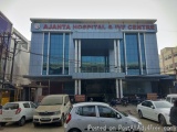 The image shows the entrance of Ajanta Hospital & IVF Centre. The building is a modern, two-story structure with a blue facad...