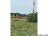 The image shows an open field with a tall radio tower in the background. The field is covered in green grass and there are a...