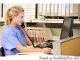 The image shows a young woman sitting at a desk in an office. She is wearing a blue scrub top and is holding a telephone rece...