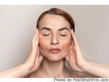 The image is a close-up portrait of a young woman with her eyes closed and her hands gently touching her face. She appears to...