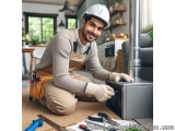 In this image, we can see a young man wearing a white hard hat and overalls, kneeling on the floor in a kitchen. He is holdin...