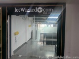 The image shows the entrance of a building with a glass door. The door is black with the words "letWizard.com" written in whi...
