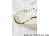 The image shows a gold-colored snake-like object on a white background. The snake appears to be made of a shiny, metallic mat...