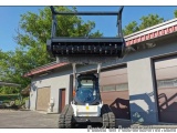 The image shows a skid steer loader parked in front of a building with a red roof. The loader is white and black in color and...
