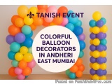The image shows a colorful balloon arch made up of multiple balloons in different colors - orange, yellow, blue, purple, and...