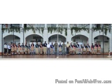 The image shows a group of people standing in a large room with a high ceiling and arches. The room appears to be a hall or a...